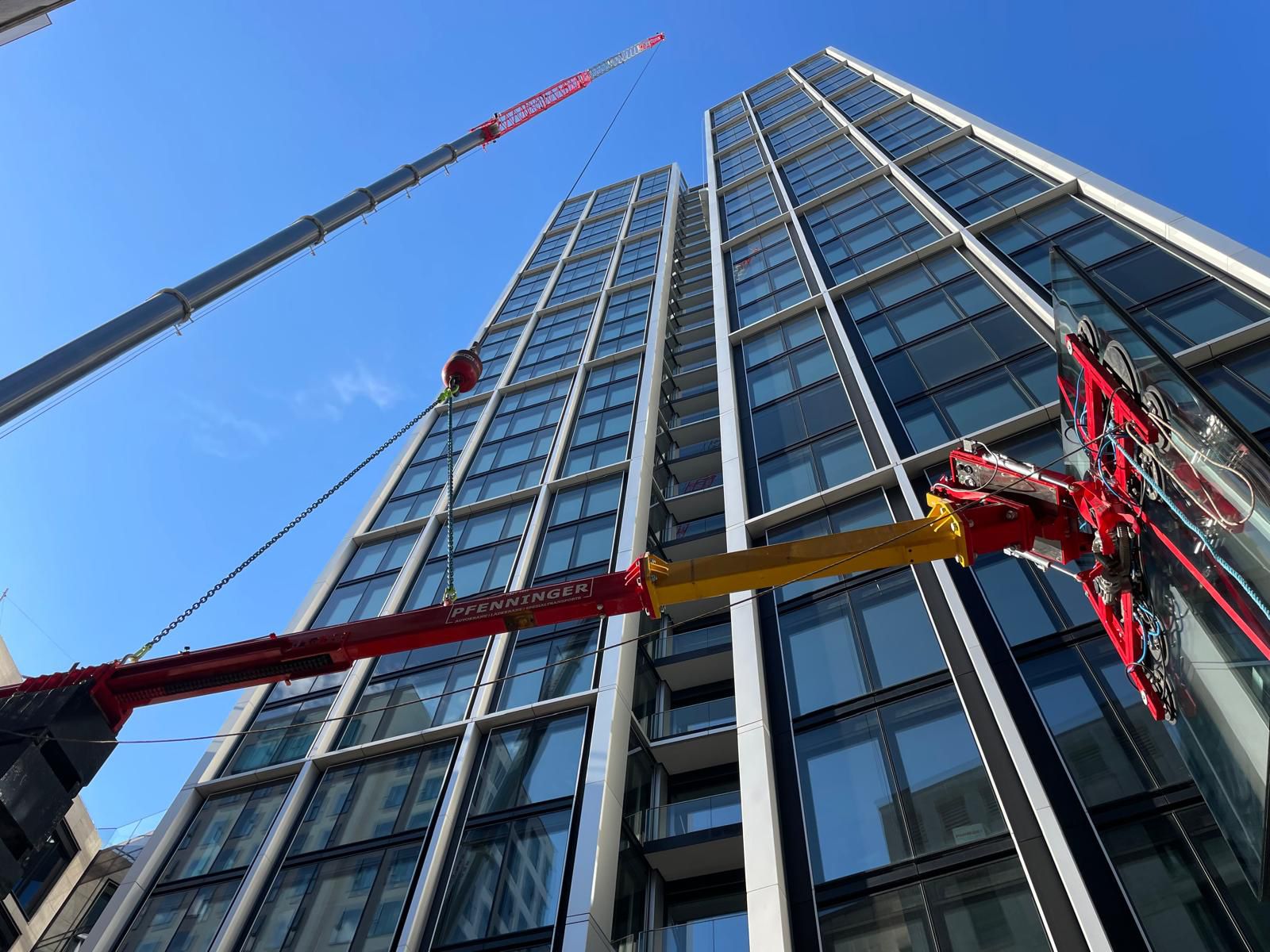 Kran hebt Bauelemente an einer modernen Hochhausfassade.