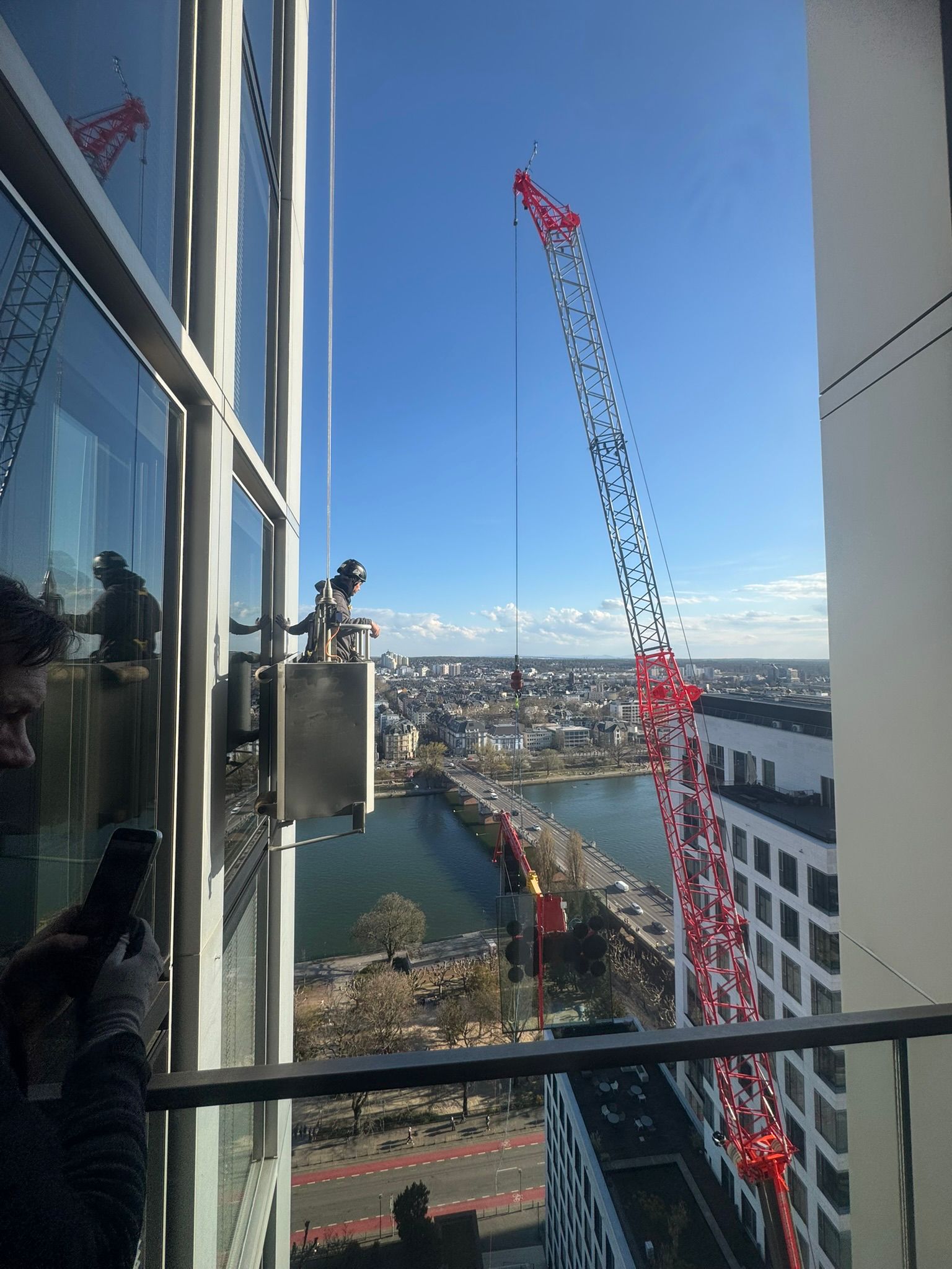 Großer Turmdrehkran vor Hochhausanlage mit Blick über die Stadt.